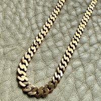 Gold chain necklace on a textured beige surface