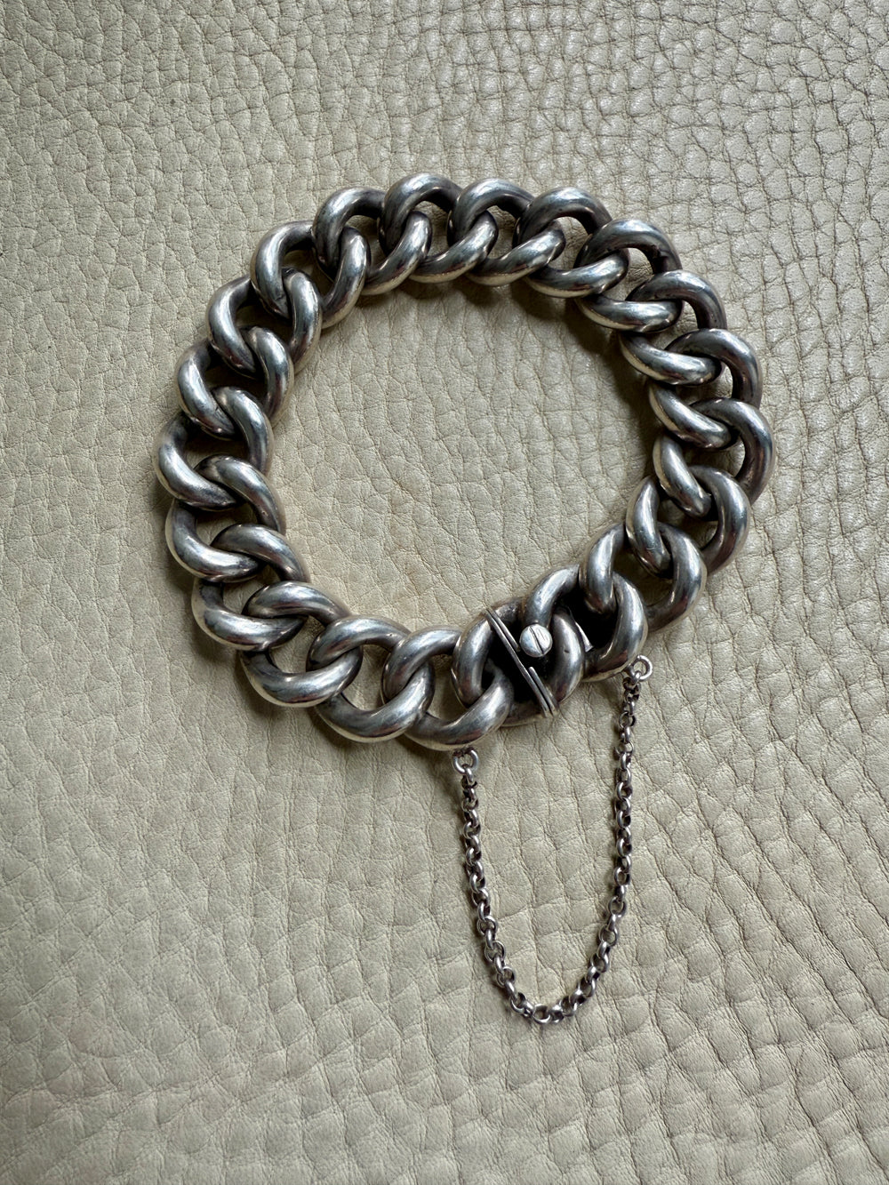 Silver chain bracelet on a textured beige surface