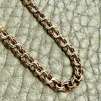 gold chain bracelet on a textured light gray background