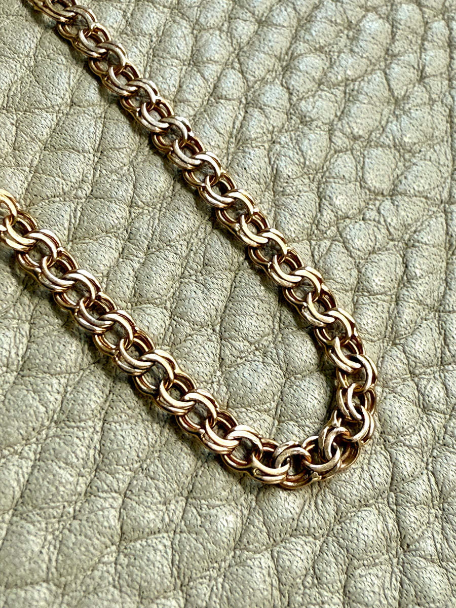 gold chain bracelet on a textured light gray background