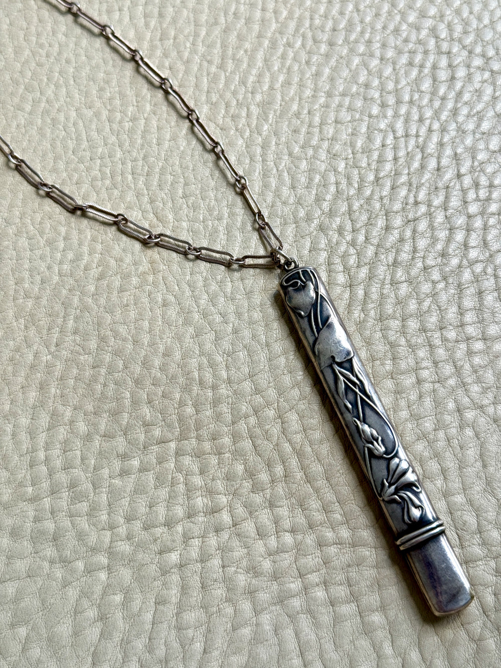 Silver necklace with a decorative pendant on a textured surface