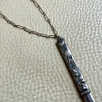 Silver necklace with a decorative pendant on a textured surface