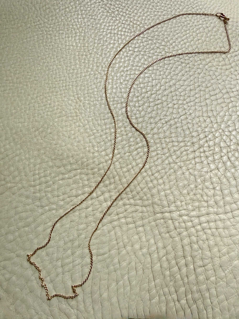 Gold necklace on a textured beige surface