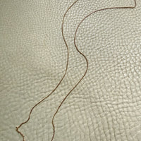 Gold necklace on a textured beige surface