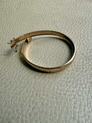 Gold bracelet on a textured light gray surface