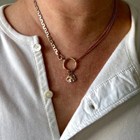 Necklace with a pendant worn by a person in a white shirt.