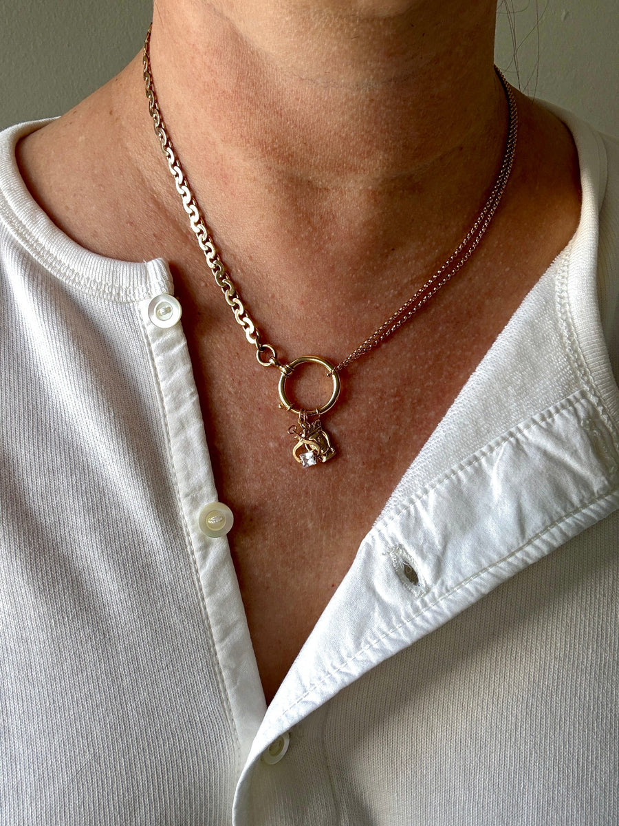Necklace with a pendant worn by a person in a white shirt.