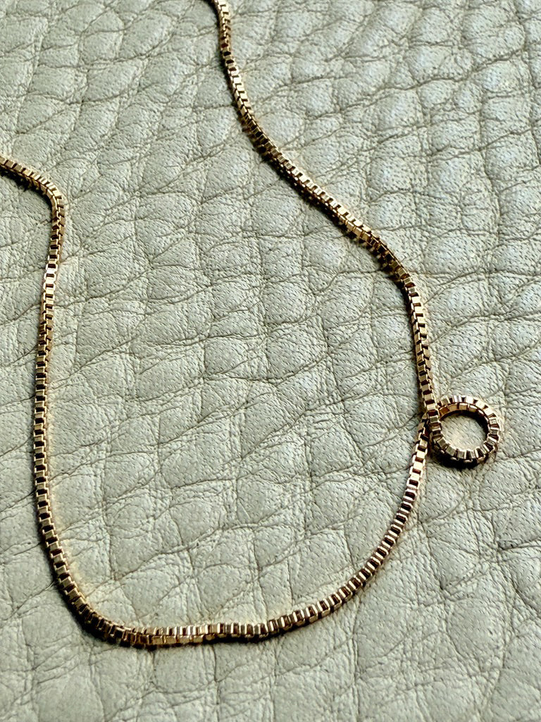 18k Gold box chain necklace on a textured light gray surface