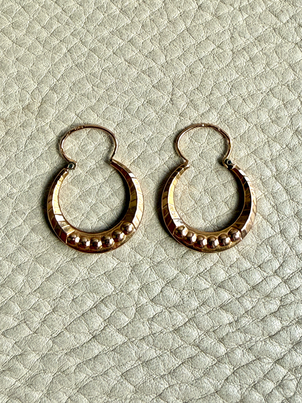 Pair of French vintage 18k Gold hoop earrings on a textured light gray surface