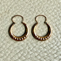 Pair of French vintage 18k Gold hoop earrings on a textured light gray surface