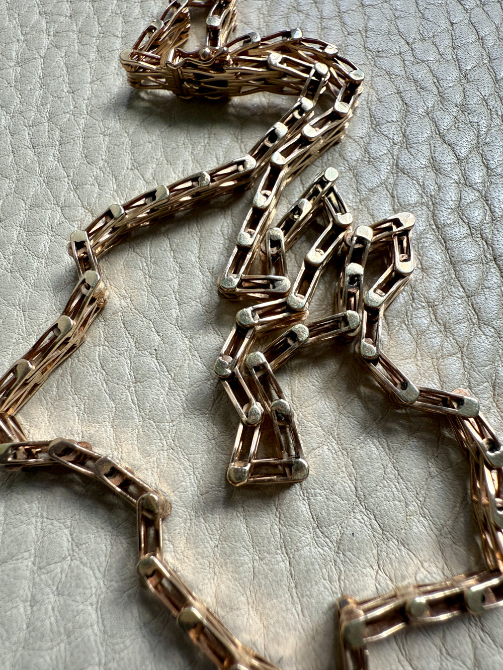 Gold chain necklace on a textured beige surface