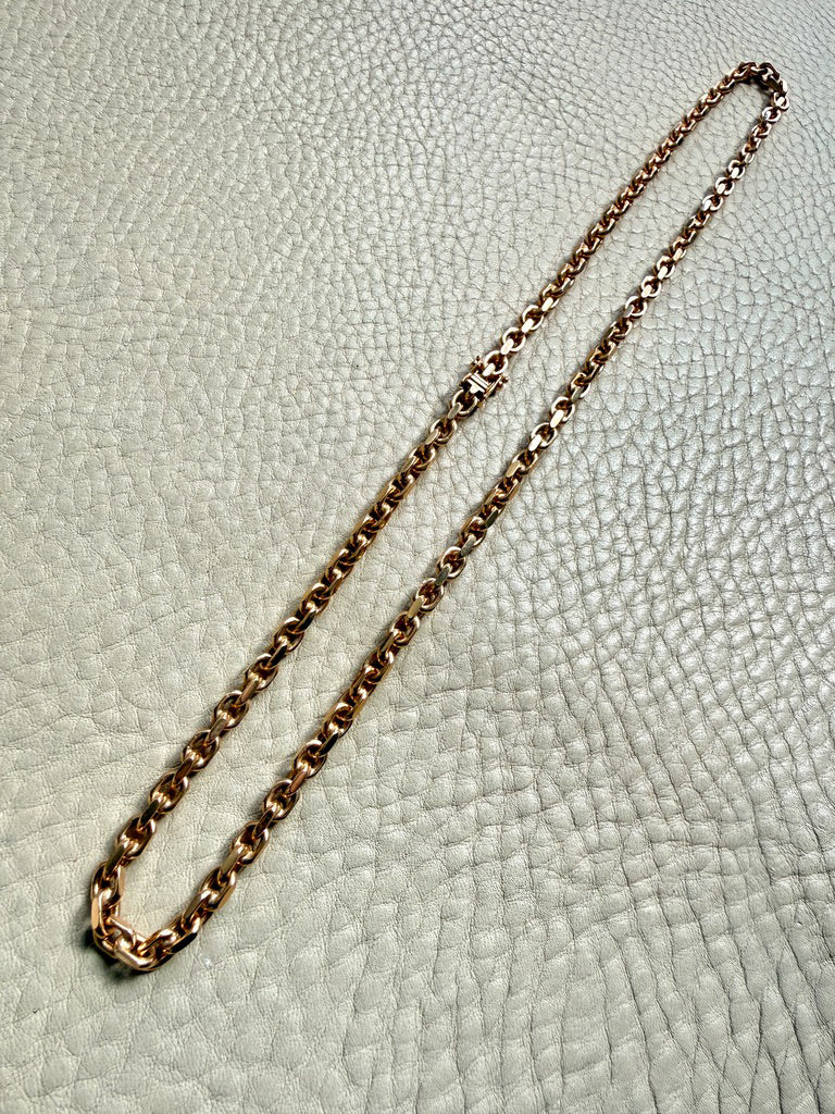 18k Gold chain biker link on a textured light gray background