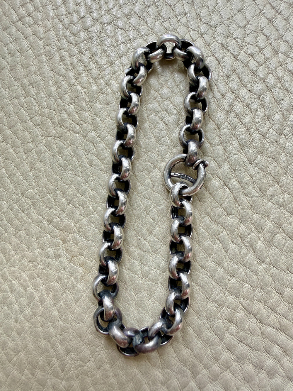 Silver chain bracelet on a textured beige surface