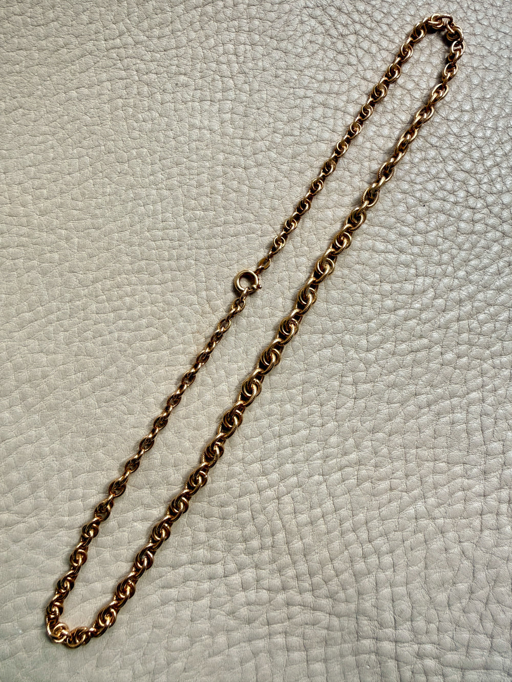 Gold chain necklace on a textured light gray background