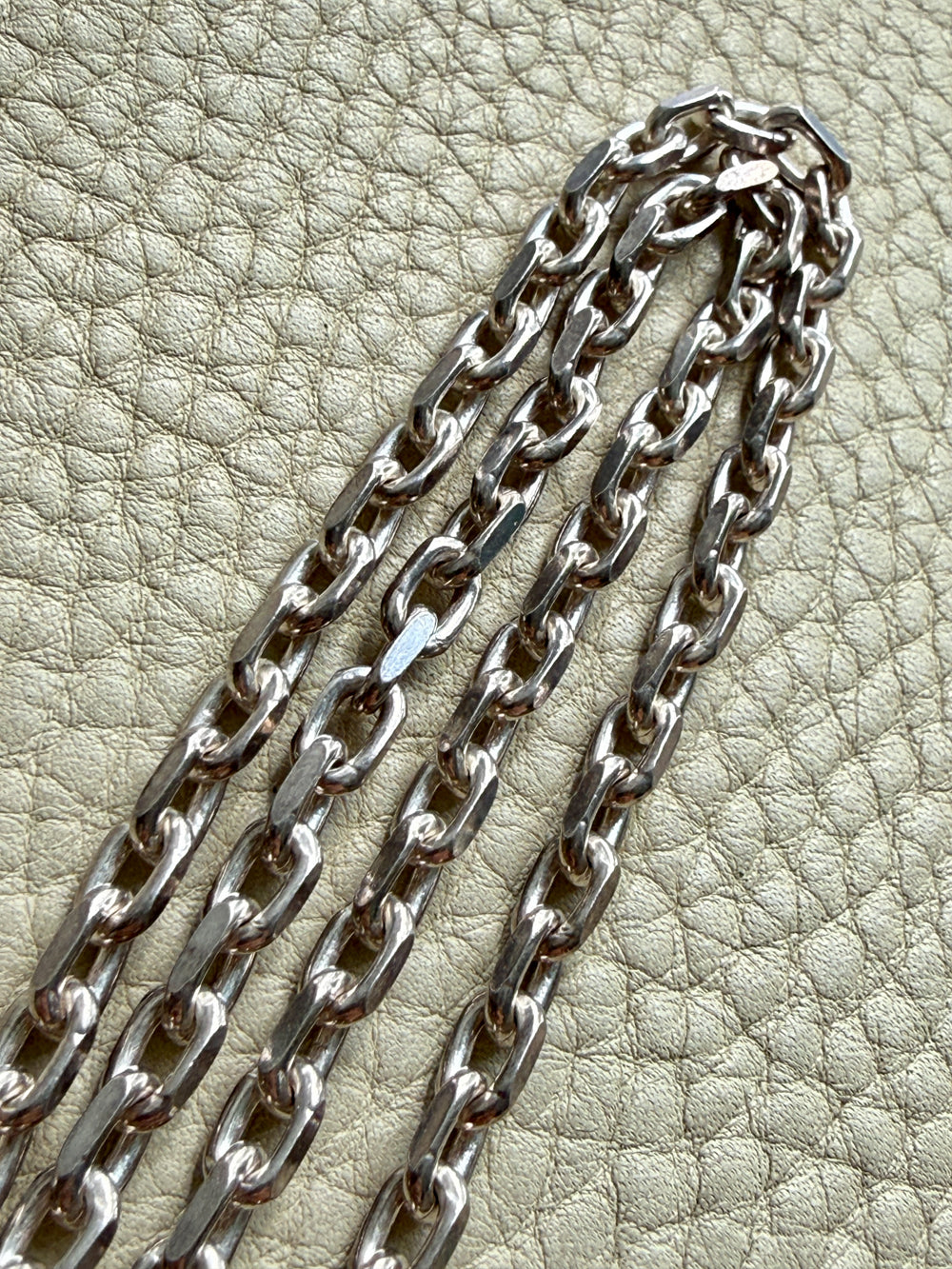 Silver chain on a textured beige surface
