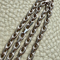 Silver chain on a textured beige surface