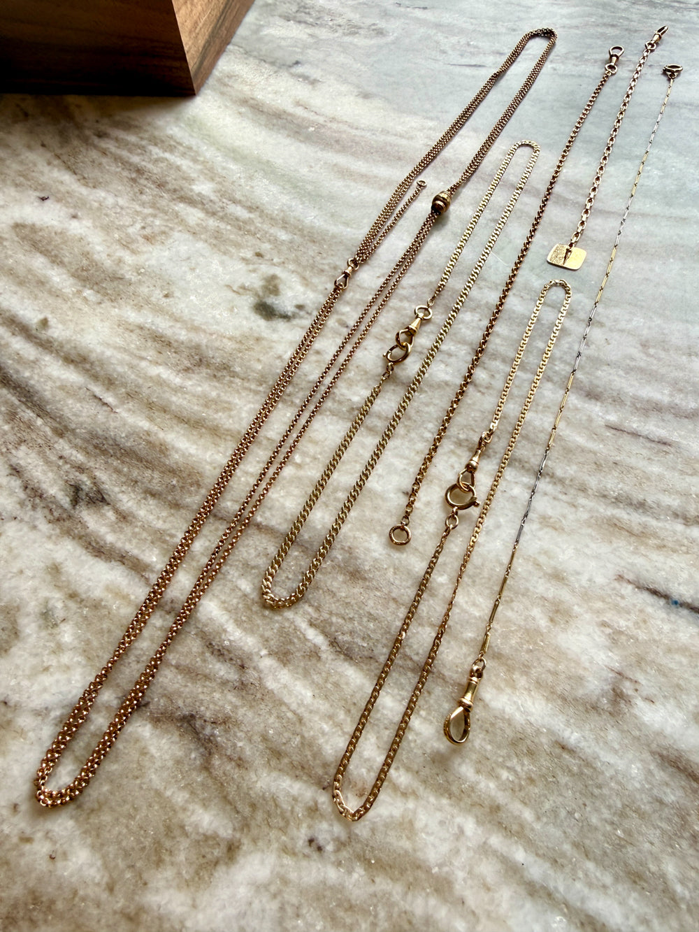 Gold watch chain necklaces on a marble surface