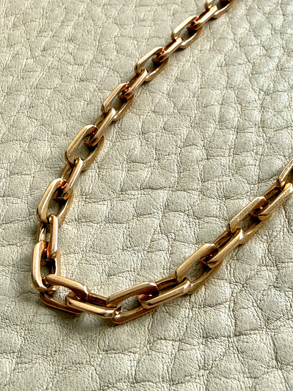Gold chain necklace on a textured light gray background