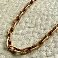 Gold chain necklace on a textured light gray background