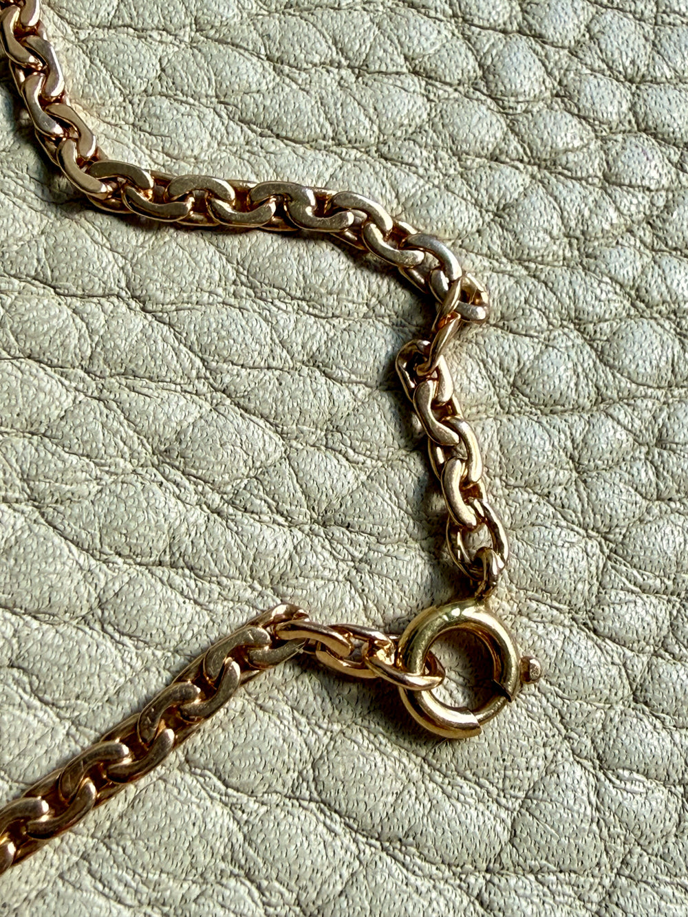 Gold chain necklace on a light green textured surface