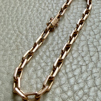 18k gold biker chain bracelet on a textured gray surface