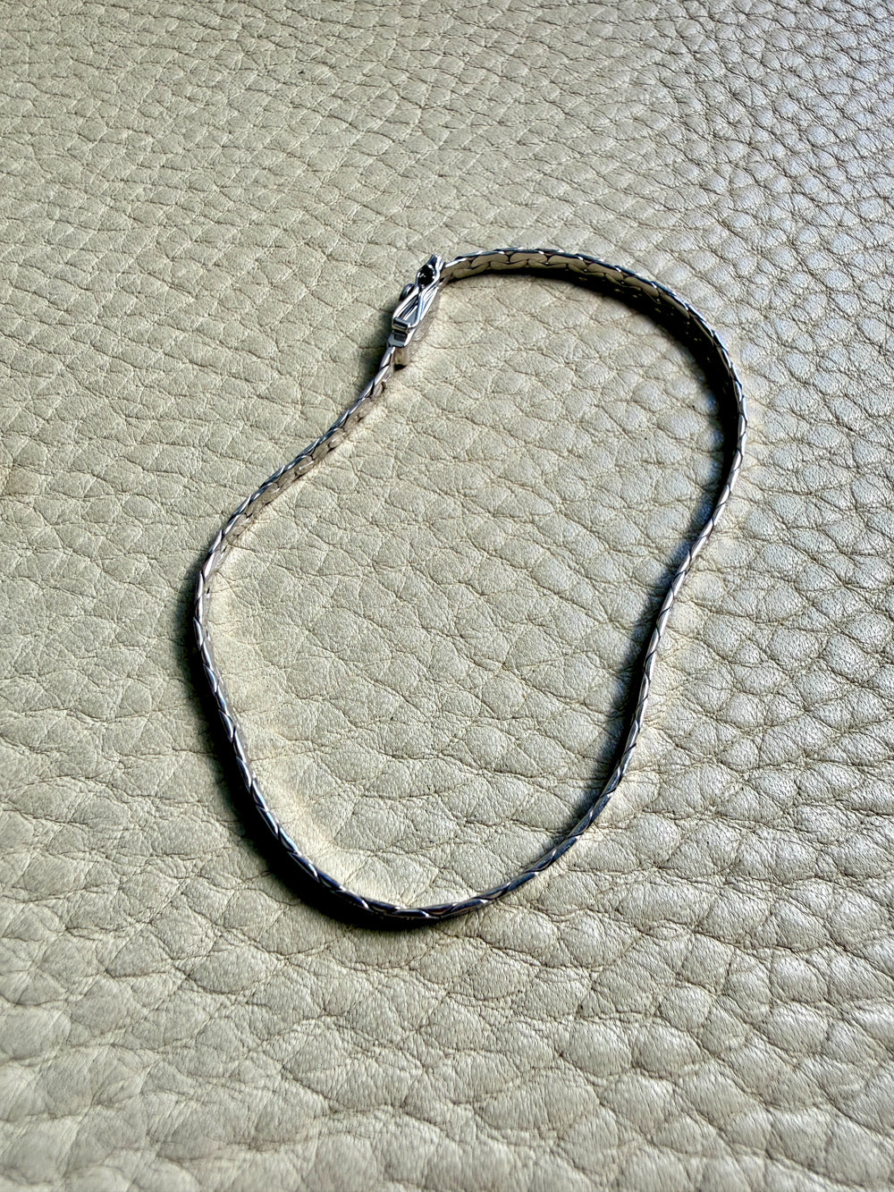 14k white gold bracelet on a textured beige surface