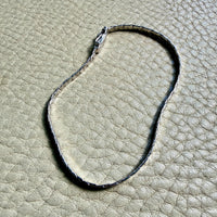 14k white gold bracelet on a textured beige surface