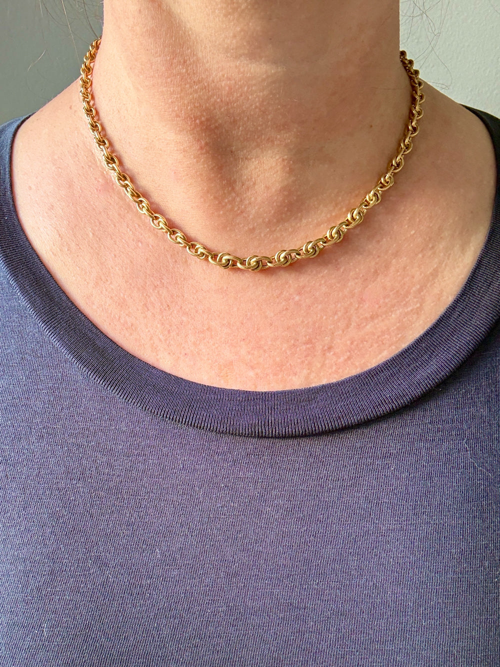 Gold chain necklace worn by a person with a black shirt