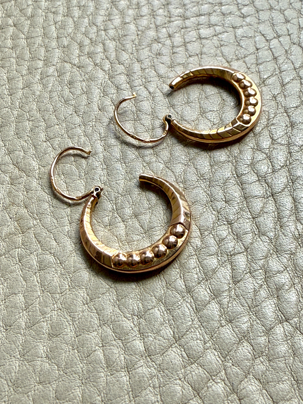 Pair of gold hoop earrings on a textured light gray surface