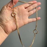 18k Gold vintage watch chain necklace held by a hand against a gray background