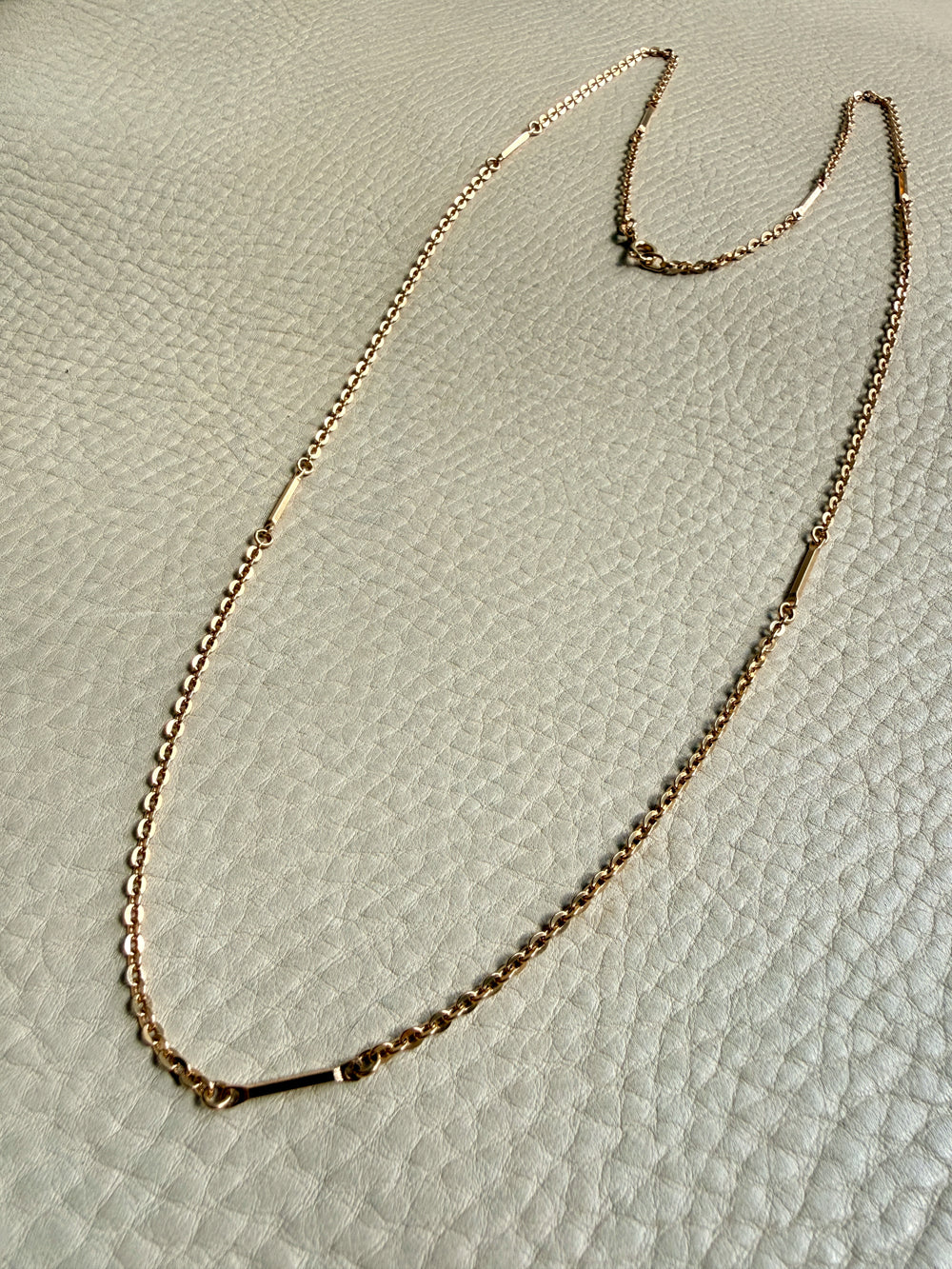 Gold chain necklace on a textured beige surface