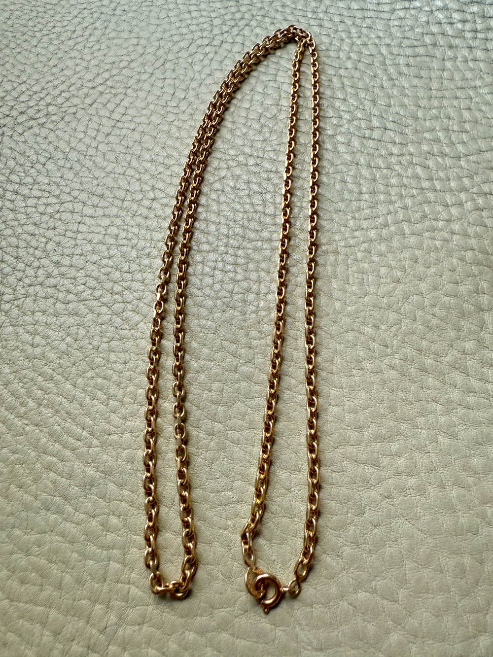 Gold chain necklace on a textured light gray background