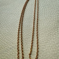 Gold chain necklace on a textured light gray background