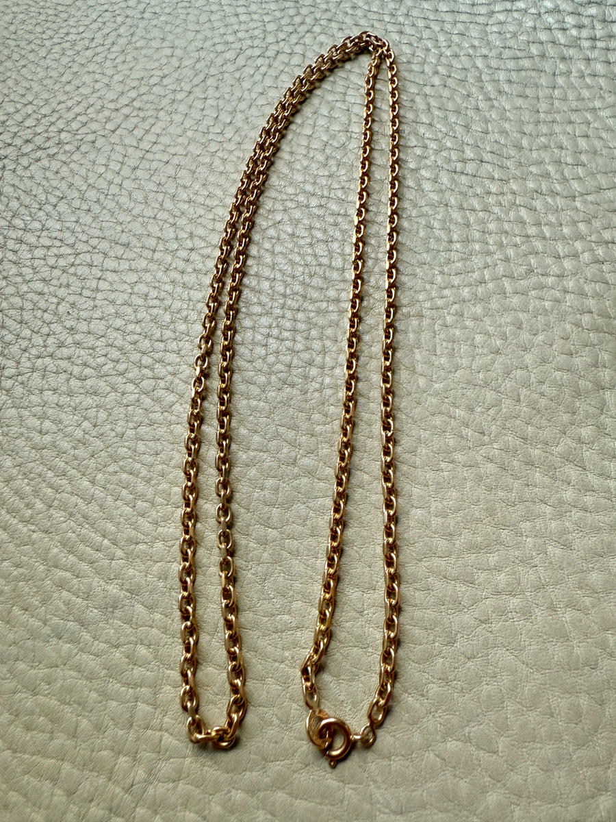 Gold chain necklace on a textured light gray background
