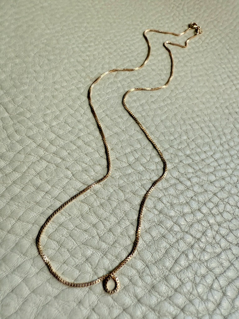 Gold necklace on a textured light gray surface