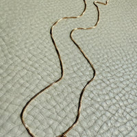 Gold necklace on a textured light gray surface