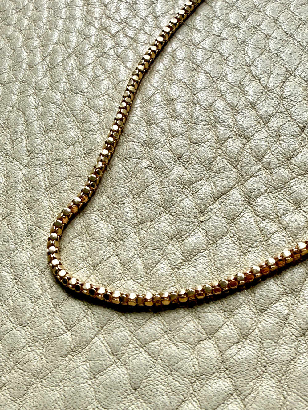 Gold chain on a textured light gray surface