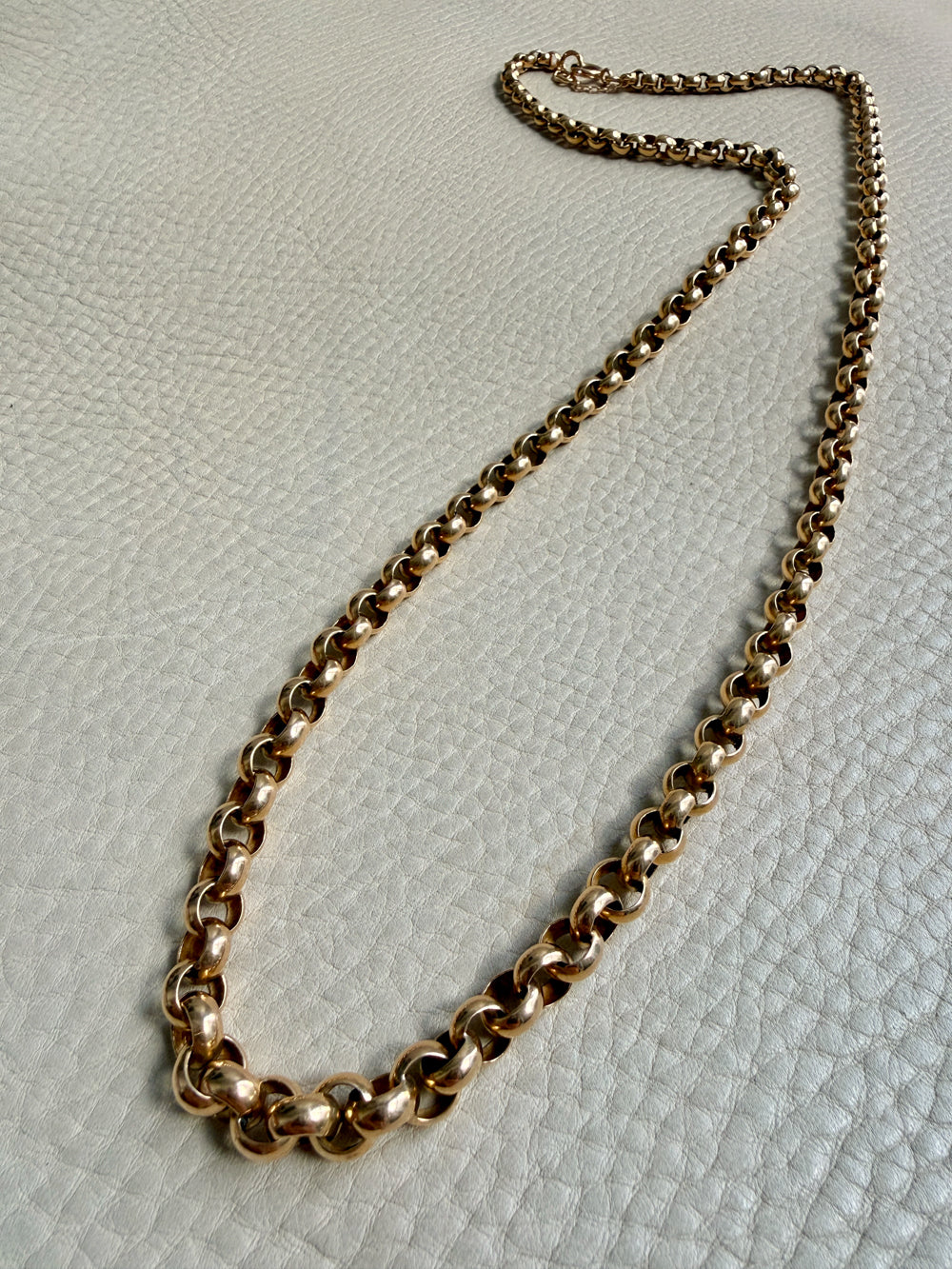 Gold chain necklace on a textured light gray surface