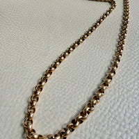 Gold chain necklace on a textured light gray surface