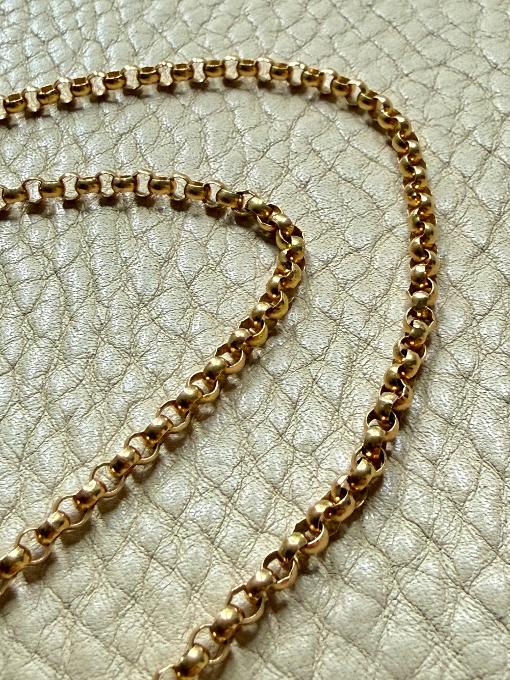 18k Gold antique rolo link necklace on a textured light gray surface