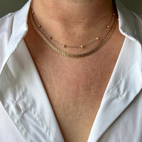 Close-up of a person wearing a white shirt with gold necklaces.