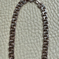 Silver chain necklace on a textured light green background