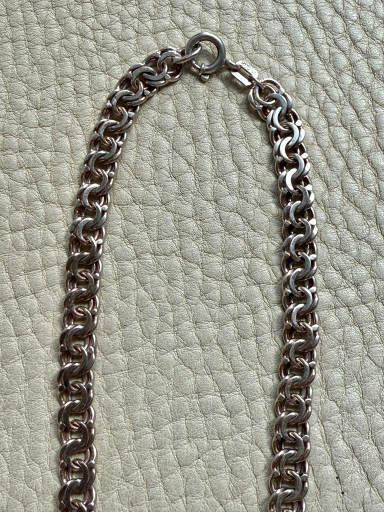 Silver chain necklace on a textured light green background