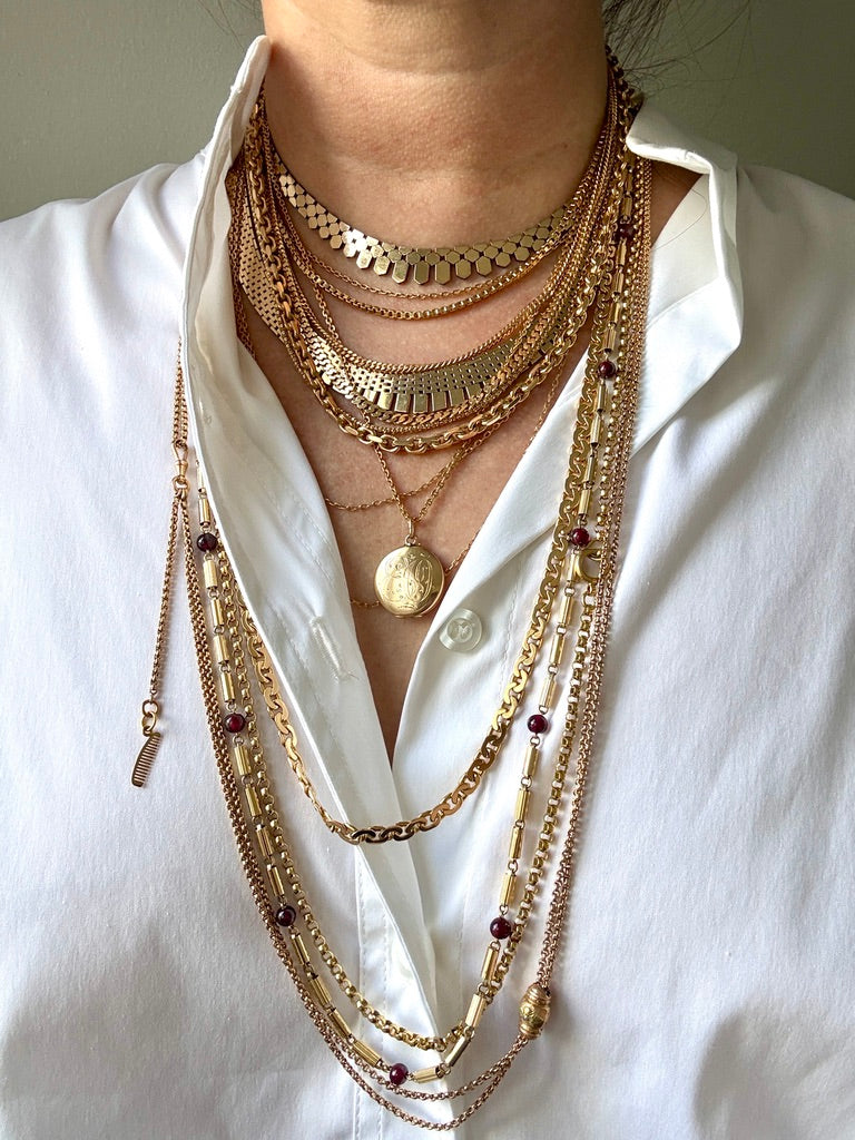vintage gold necklaces stacked on a person in a white shirt. penelopepenelope.com