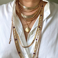 vintage gold necklaces stacked on a person in a white shirt. penelopepenelope.com