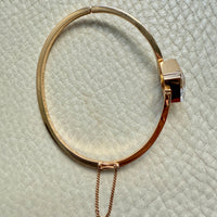 Gold bracelet with a chain on a textured light green surface