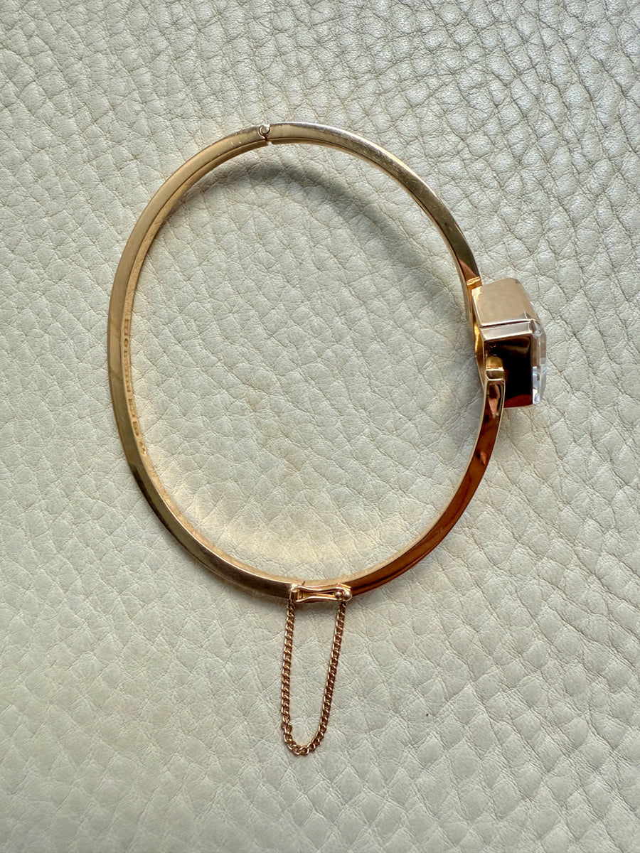 Gold bracelet with a chain on a textured light green surface