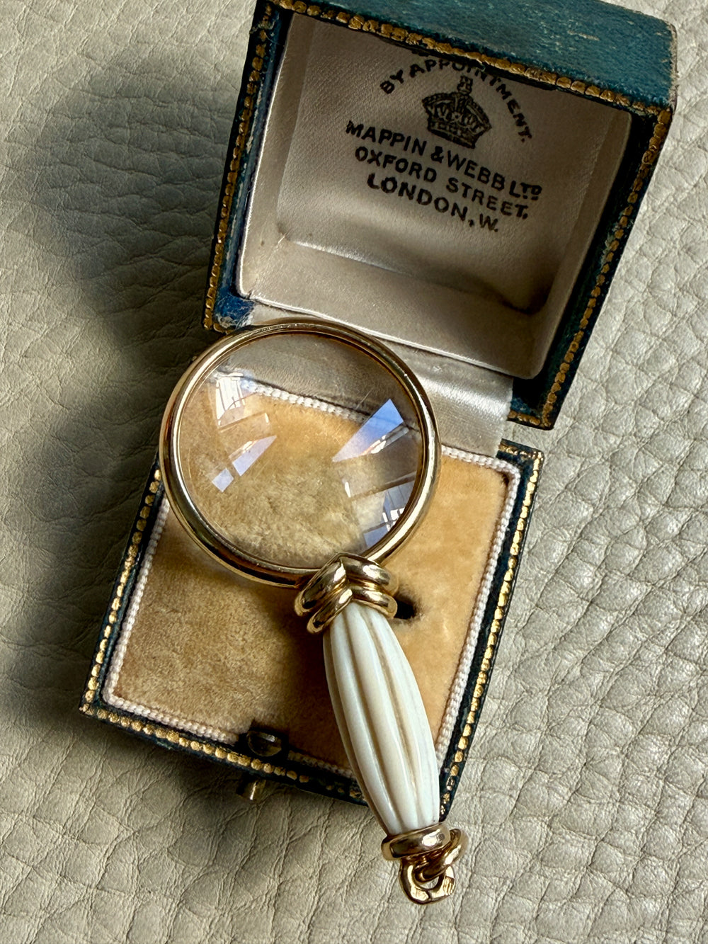 antique magnifying glass with a white handle in an open box on a textured surface