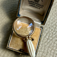 antique magnifying glass with a white handle in an open box on a textured surface