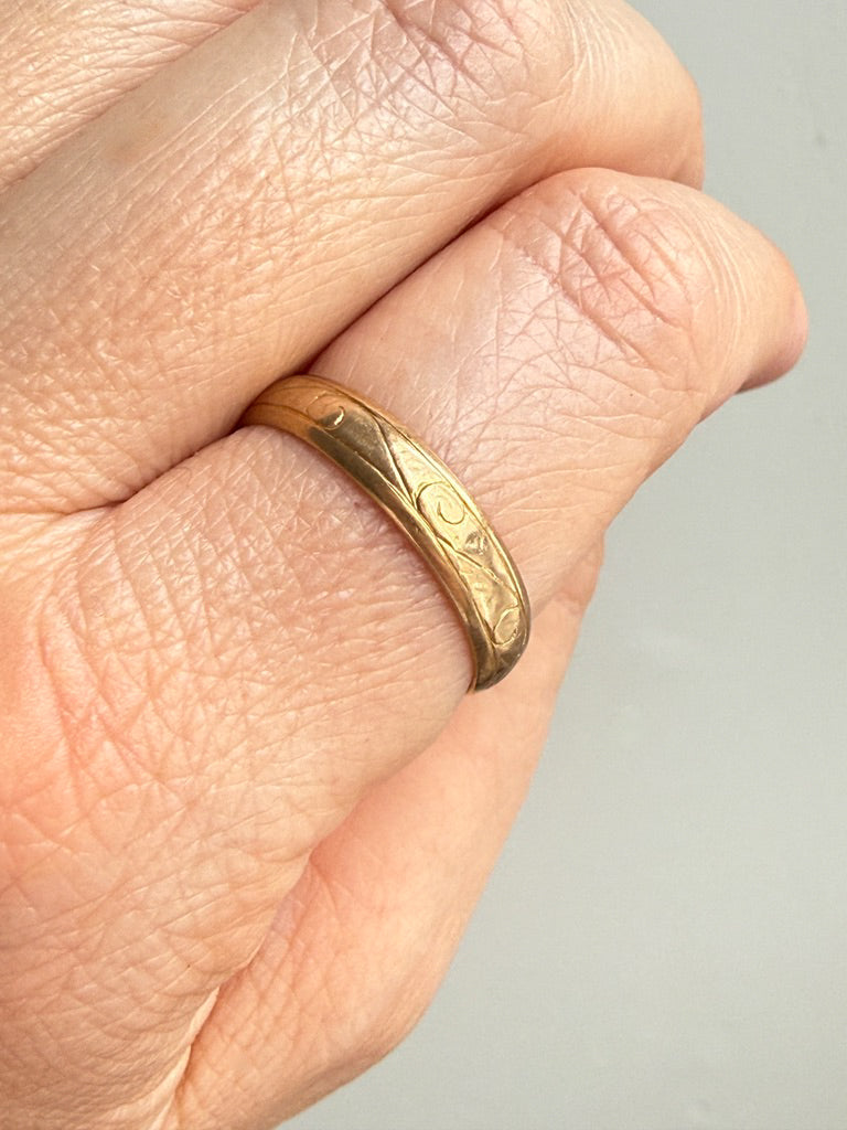 Gold ring on a person's finger against a neutral background